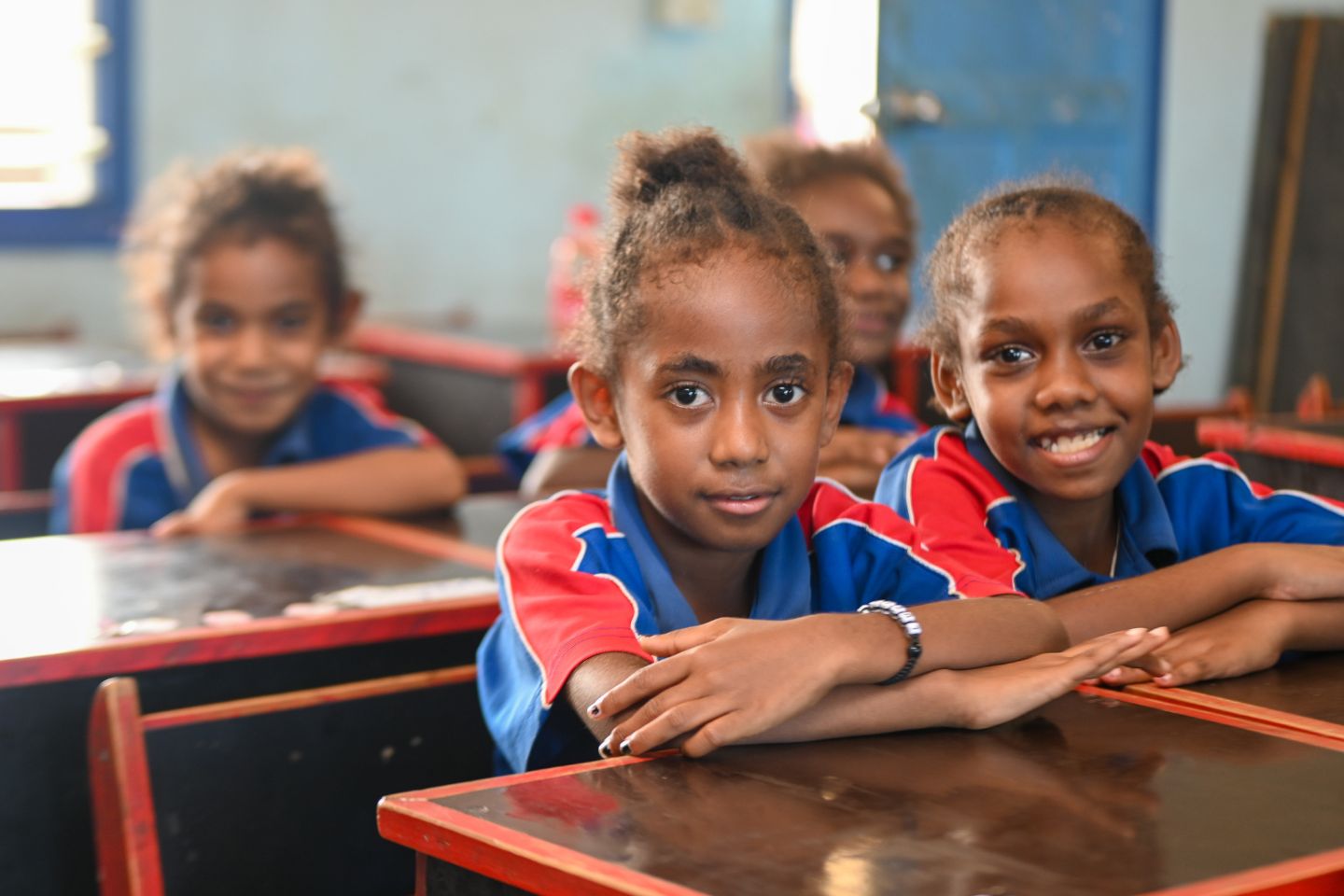 Children sitting at their desks and smiling in Vanuatu school.