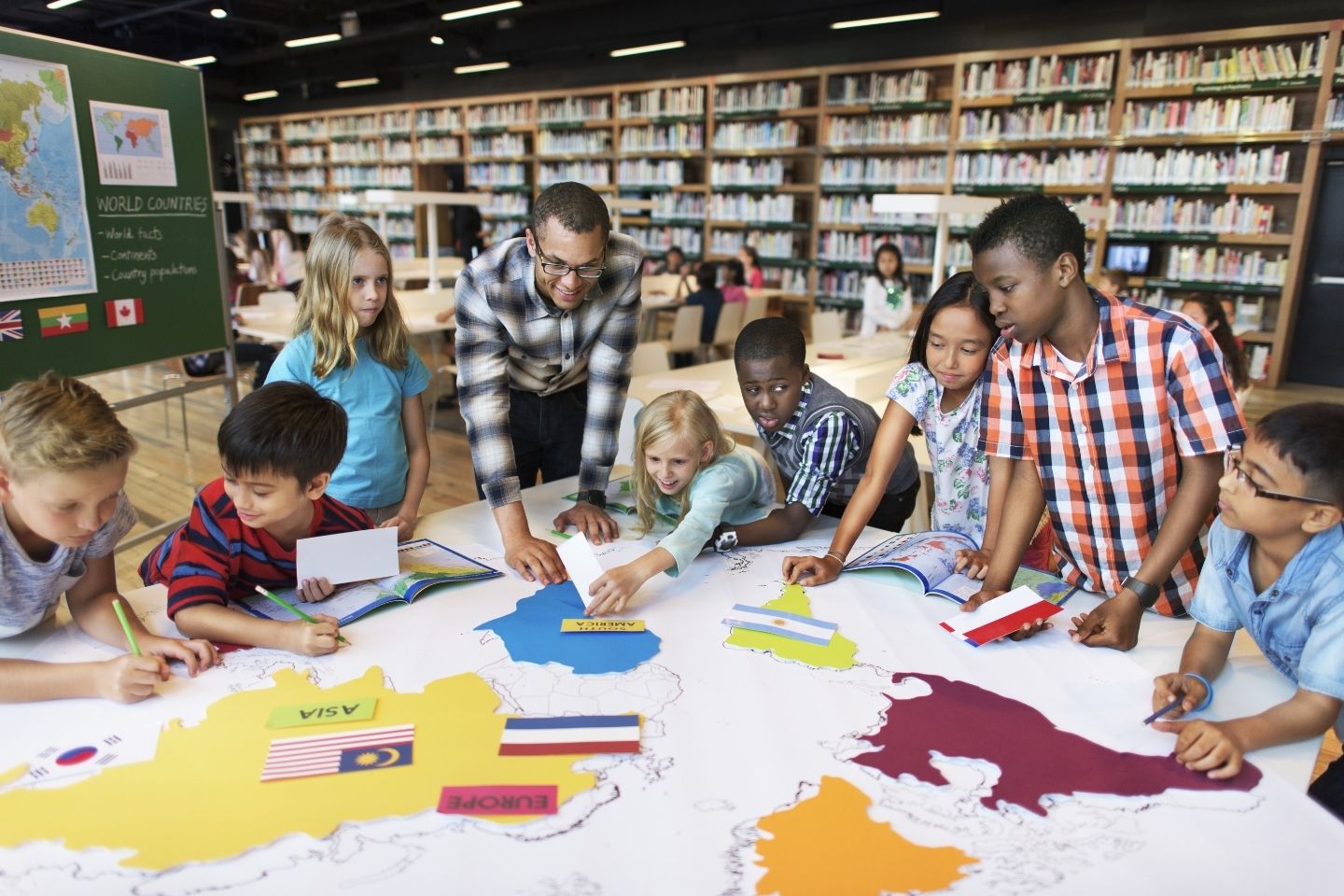 Students participate in activity with teacher to label countries of the world.