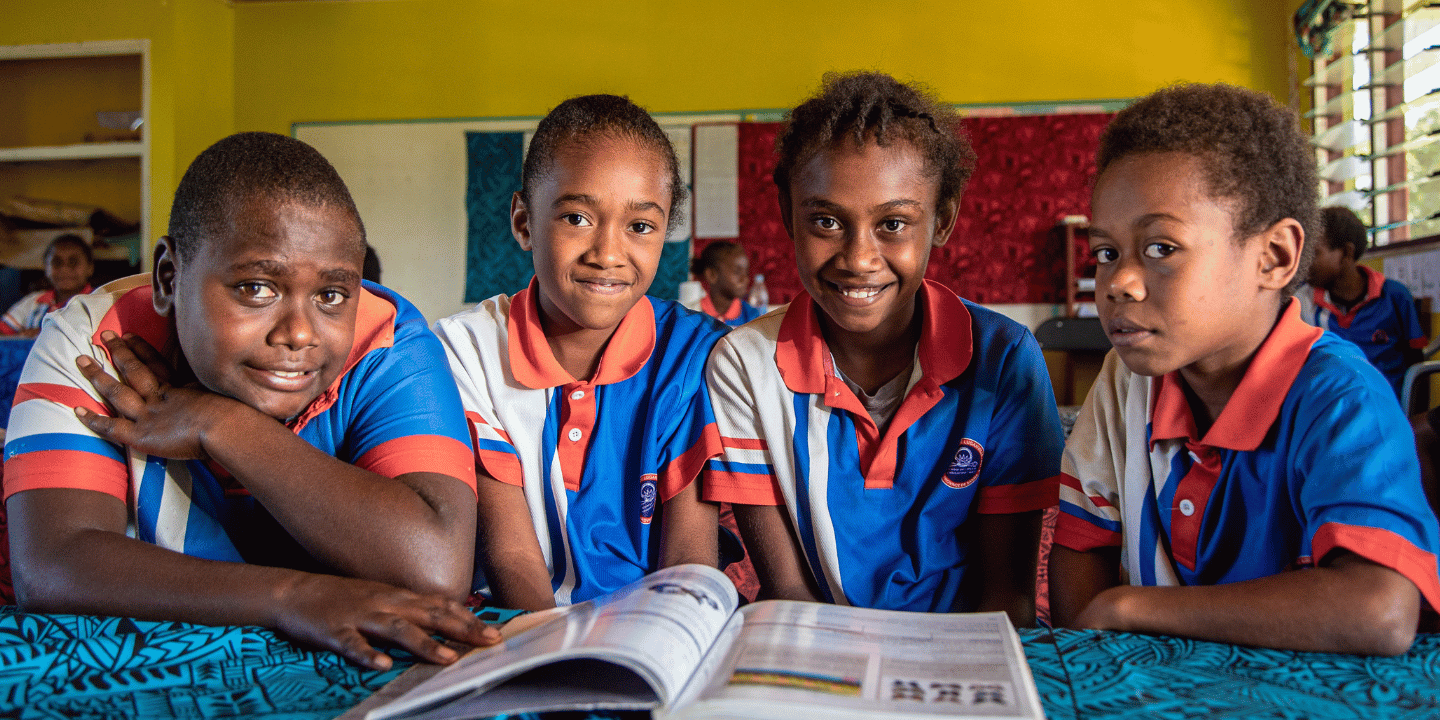Four students smile for camera at school in Vanuatu