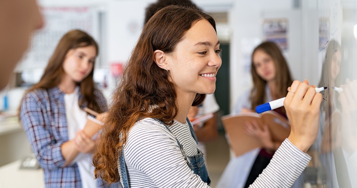 Image of student using whiteboard marker on a whiteboard.