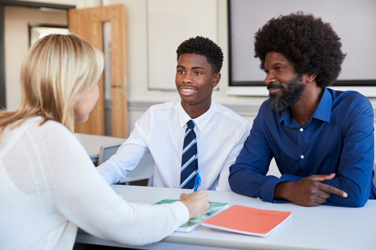 Stock image of Father And Teenage Son Having Discussion With Female Teacher At High School Parents Evening